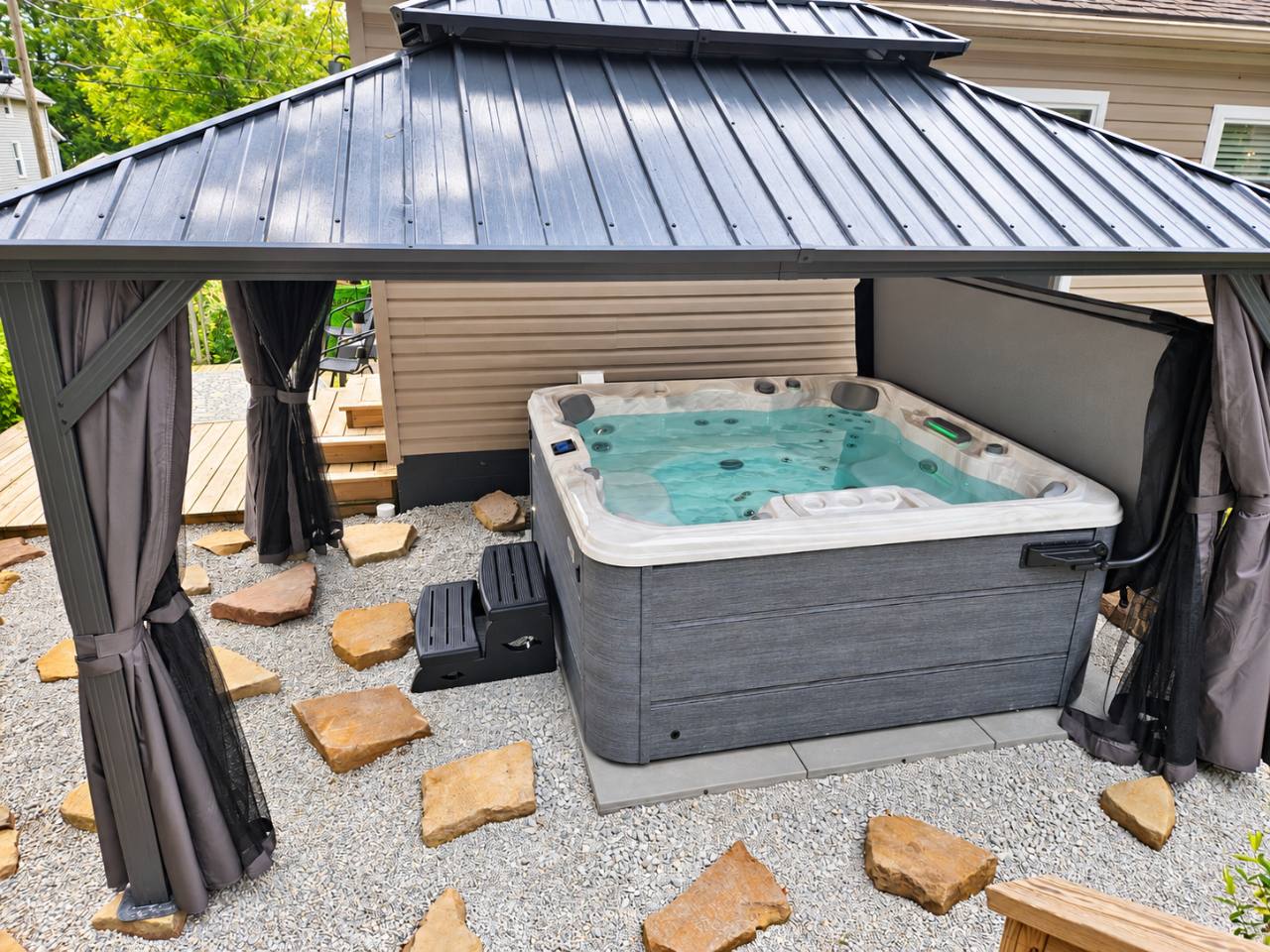Private six-person hot tub beneath a curtained gazebo at The Oasis of Massillon